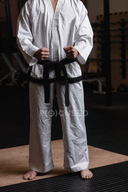 Low section of man in kimono karate standing in fitness studio — Stock Photo