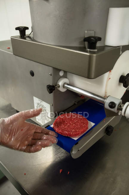 Hand preparing a raw hamburger patty in the butchers shop — Stock Photo