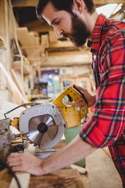 Man cutting wooden plank with electric saw in boatyard — Stock Photo