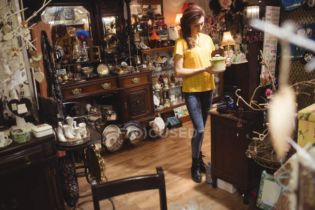 Mulher olhando para um bule vintage na loja de antiguidades — Fotografia de Stock