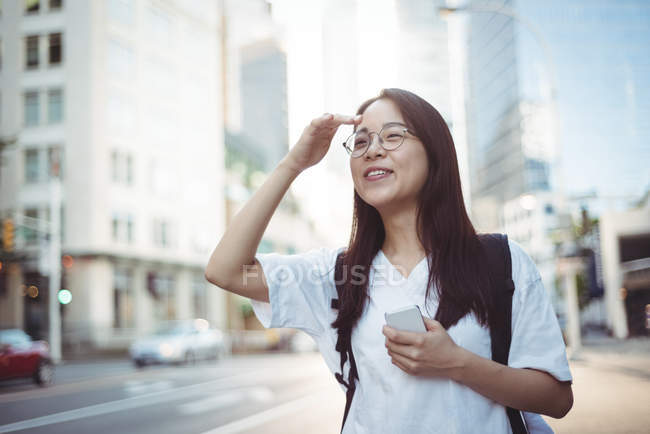 Happy young woman shielding her eyes on street — Stock Photo