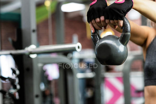 Femme soulevant kettlebell à la salle de gym — Photo de stock