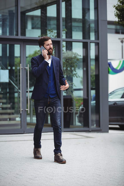 Бизнесмен разговаривает по мобильному телефону за пределами офиса — стоковое фото