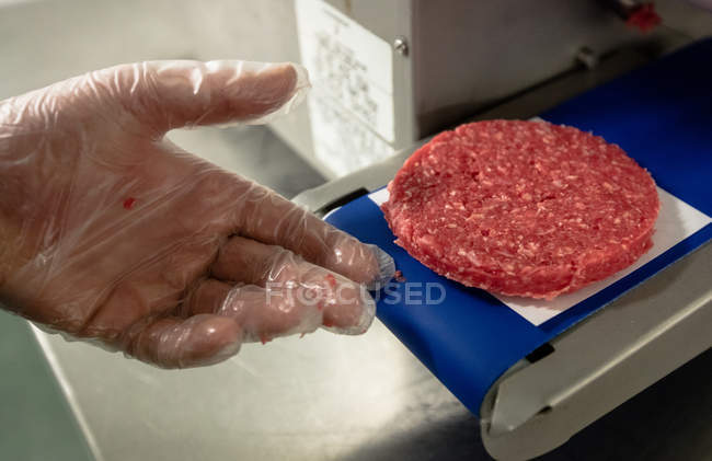 Mano preparando una hamburguesa cruda en la carnicería - foto de stock