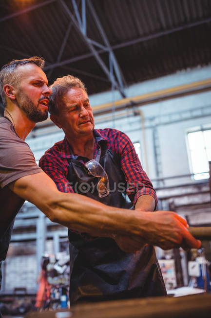 Glassblowers heating a glass in furnace at glassblowing factory — Stock Photo