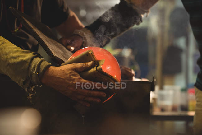 Imagem cortada de sopradores de vidro moldando peça de vidro soprado com pano molhado na fábrica de sopro de vidro — Fotografia de Stock