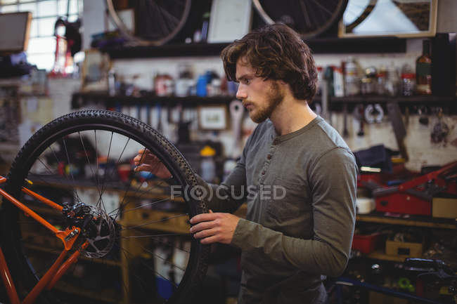 Mechaniker begutachtet in Werkstatt ein Fahrradrad — Stockfoto