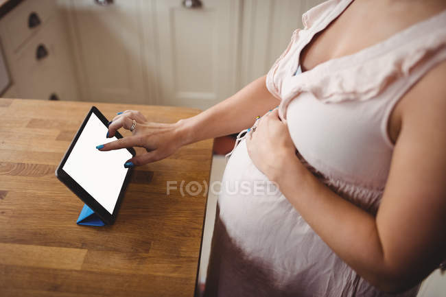 Cropped image of pregnant woman using digital tablet in kitchen at home — Stock Photo
