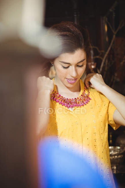 Woman wearing a vintage necklace in antique shop — Stock Photo