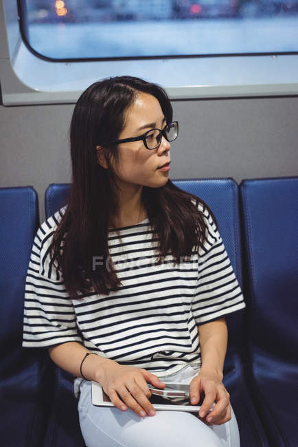 Задумчивая молодая женщина держит цифровой планшет во время путешествия на корабле — стоковое фото