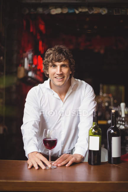 Portrait of bar tender with glass of red wine at bar counter — Stock Photo