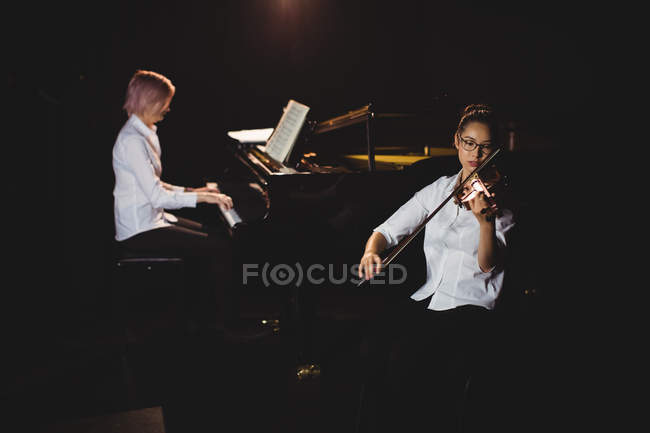 Deux étudiantes jouant du violon et du piano dans un studio — Photo de stock