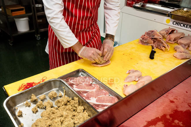 Macellaio che prepara un involtino di pollo e bistecca in macelleria — Foto stock