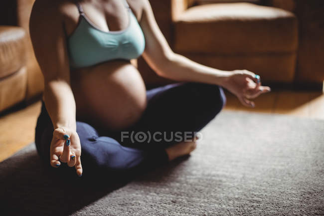Обрізаний образ вагітної жінки, що виконує йогу у вітальні вдома — стокове фото