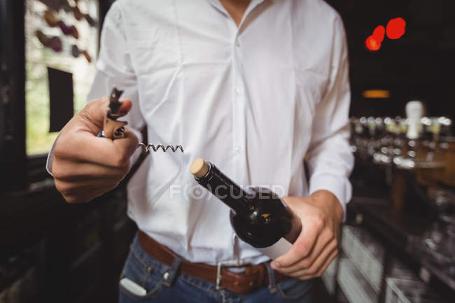 Sezione centrale del bar tender che apre una bottiglia di vino al bancone del bar — Foto stock
