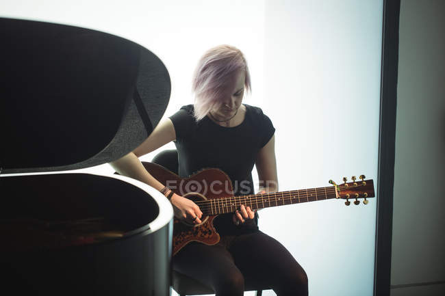 Mujer tocando una guitarra en la escuela de música - foto de stock