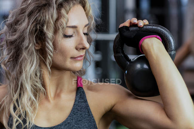 Belle femme soulevant kettlebell à la salle de gym — Photo de stock