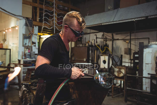 Glassblower giving final touch to piece of glass with glassblowing torch at glassblowing factory — Stock Photo