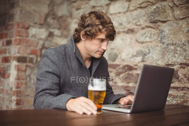 Uomo che utilizza il computer portatile al bar — Foto stock
