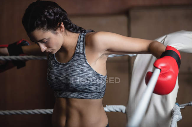 Втомилася жінка-боксер в боксерських рукавичках, що стоять на боксерському кільці в фітнес-студії — стокове фото
