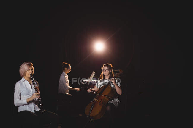 Три студентки играют на контрабасе, кларнете и фортепиано в студии — стоковое фото