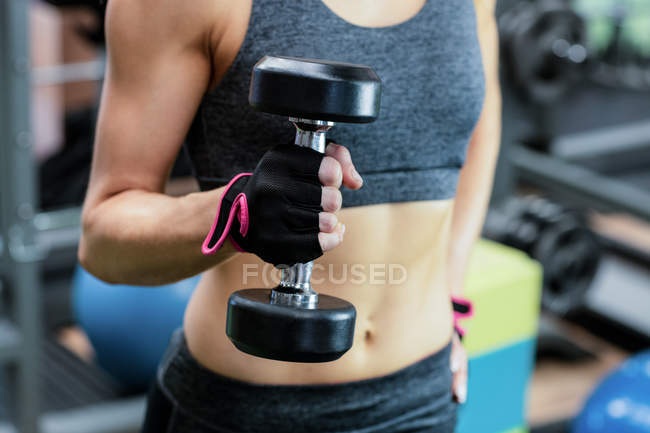 Woman lifting dumbbell at gym — Stock Photo