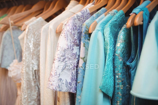Différents vêtements colorés sur un cintre au magasin de la boutique — Photo de stock