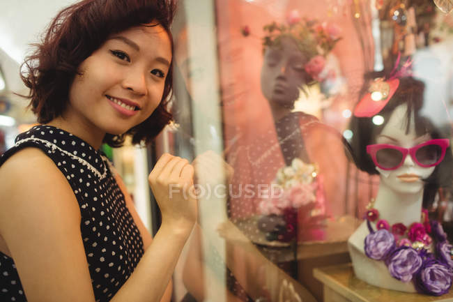 Retrato de una mujer sonriente haciendo compras por la ventana - foto de stock