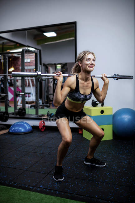 Schöne Frau trainiert mit Langhantel im Fitnessstudio — Stockfoto