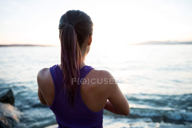 Вид ззаду жінки, що практикує йогу на пляжі в сонячний день — стокове фото