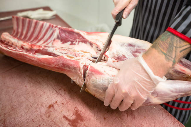 Partie médiane du boucher coupant les côtes de la carcasse de porc dans la boucherie — Photo de stock