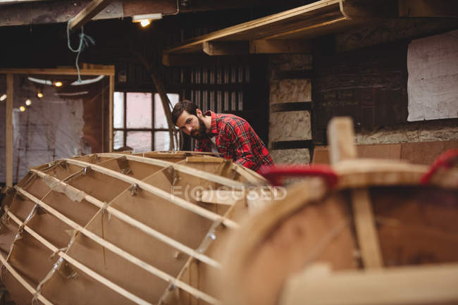 Mann bereitet Holzbootrahmen in Bootswerft vor — Stockfoto