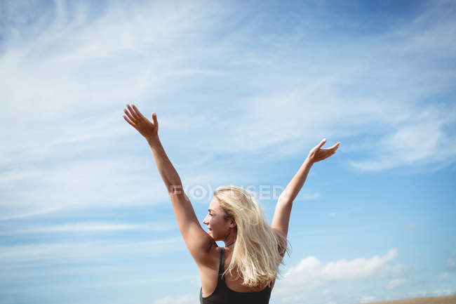Visão traseira de mulher loira atraente em pé no campo com os braços abertos — Fotografia de Stock