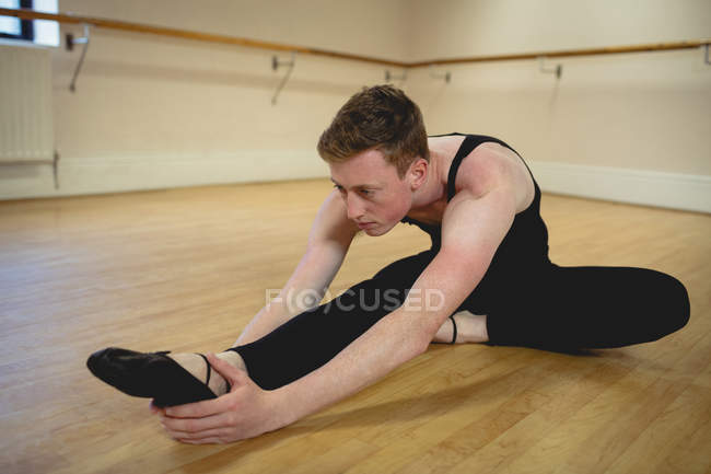 Ballerino alongamento no chão de madeira em estúdio — Fotografia de Stock