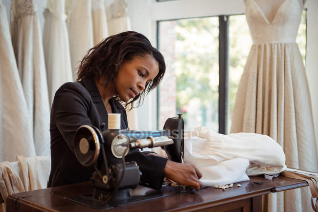 Модный дизайнер пришивает швейную машинку в студии — стоковое фото