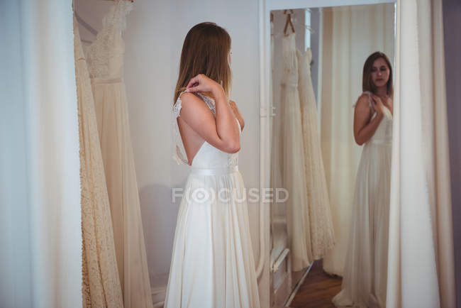 Belle femme essayant robe de mariée dans un magasin en studio — Photo de stock