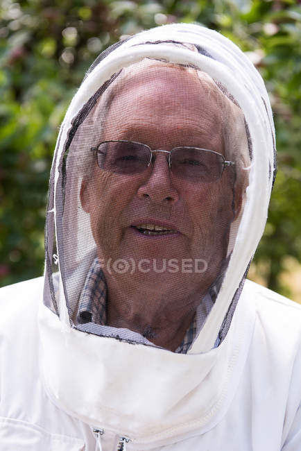 Retrato del apicultor mayor de pie en un jardín colmenar - foto de stock