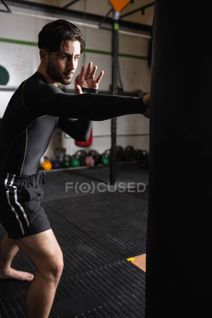 Ritratto di Boxer che pratica pugilato con sacco da boxe in palestra — Foto stock