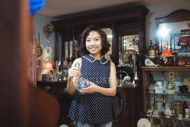 Retrato de una mujer sonriente comprando antigüedades en una tienda de antigüedades - foto de stock
