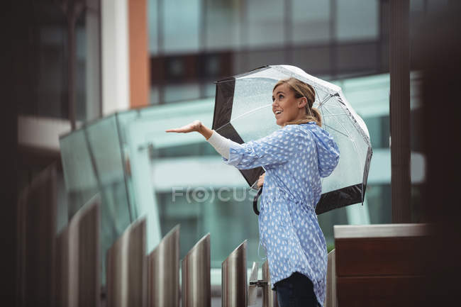 Sonriente Hermosa mujer disfrutando de la lluvia durante la temporada de lluvias - foto de stock