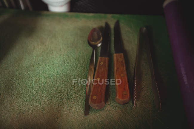 Primer plano de pinzas, cuchara y cuchillo en el mostrador de la barra - foto de stock