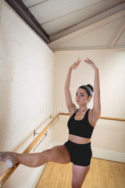 Балерина растягивается на баре в балетной студии — стоковое фото