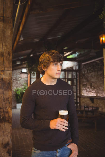 Hombre sosteniendo un vaso de cerveza en el bar - foto de stock