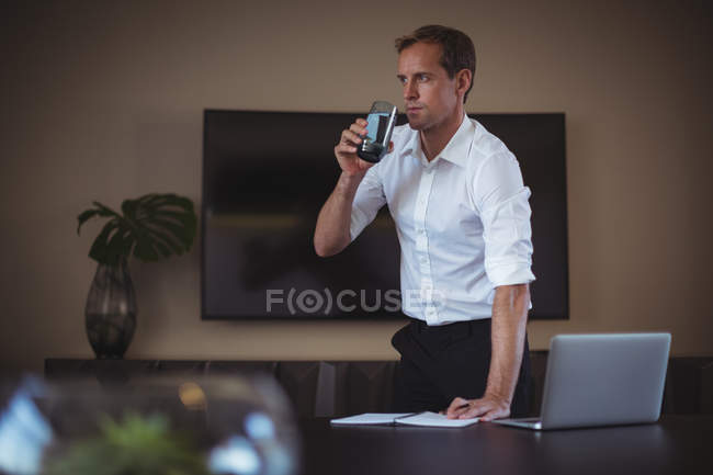 Concentrated businessman having water while working in office — Stock Photo