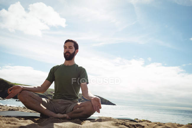 Man performing yoga on beach — Stock Photo