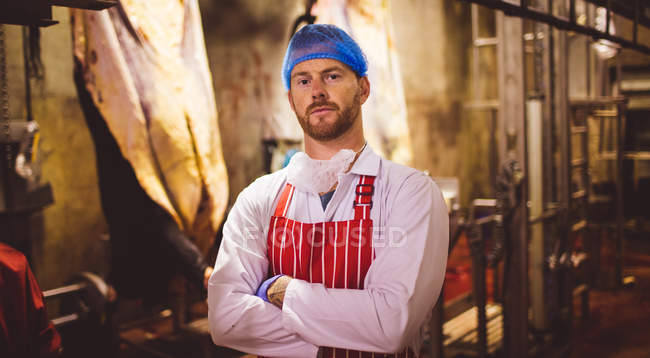 Portrait of butcher standing with arms crossed in meat storage room at butchers shop — Stock Photo