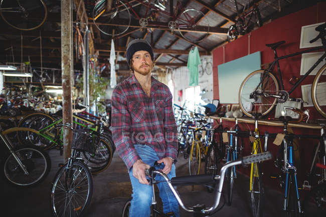 Retrato de mecânico sentado na bicicleta na loja de bicicletas — Fotografia de Stock