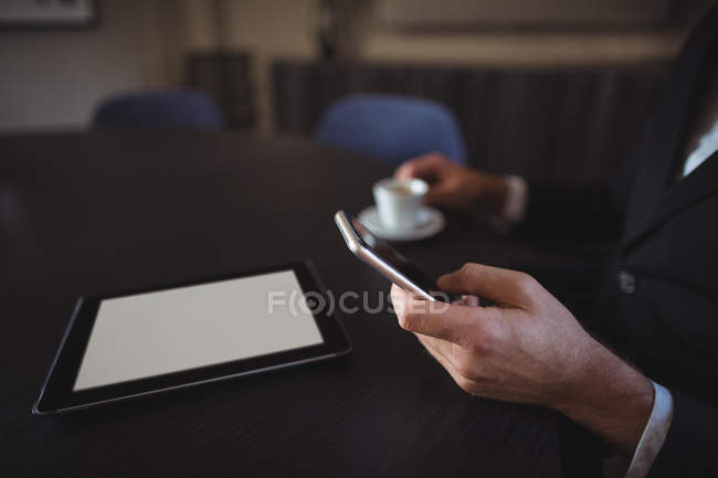Рука бізнесмена, що використовує мобільний телефон в офісі — стокове фото
