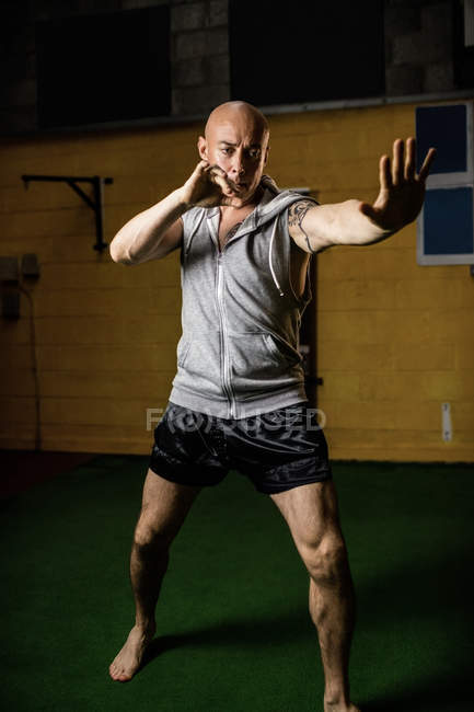 Handsome muay thai boxer practicing boxing in gym — Stock Photo
