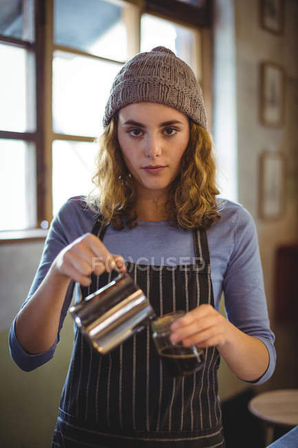 Портрет красивой официантки, готовящей кофе у стойки в мастерской — стоковое фото